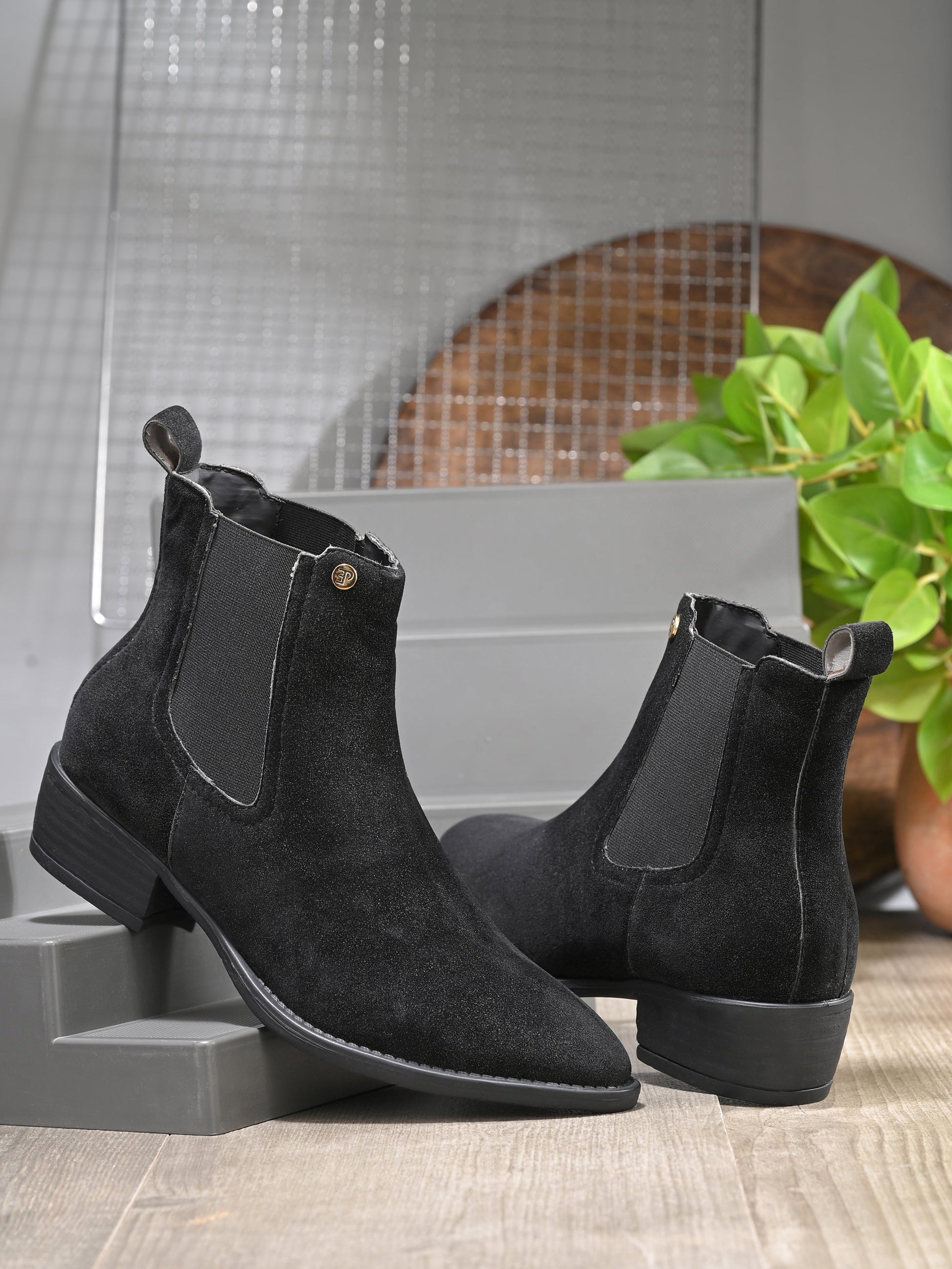 Black suede Chelsea boots with elastic side panels and a low block heel, featuring subtle gold detailing for a sleek, versatile look.