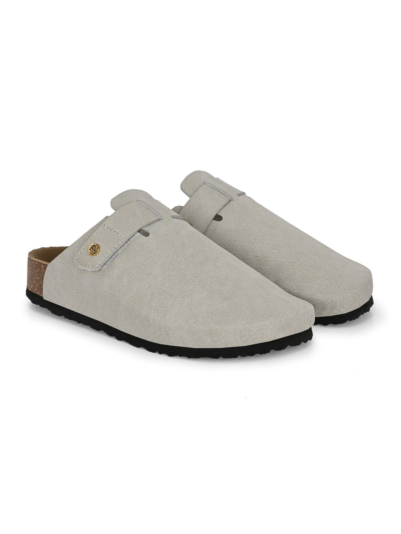 Nude suede slip-on clog with a black rubber sole and adjustable strap.