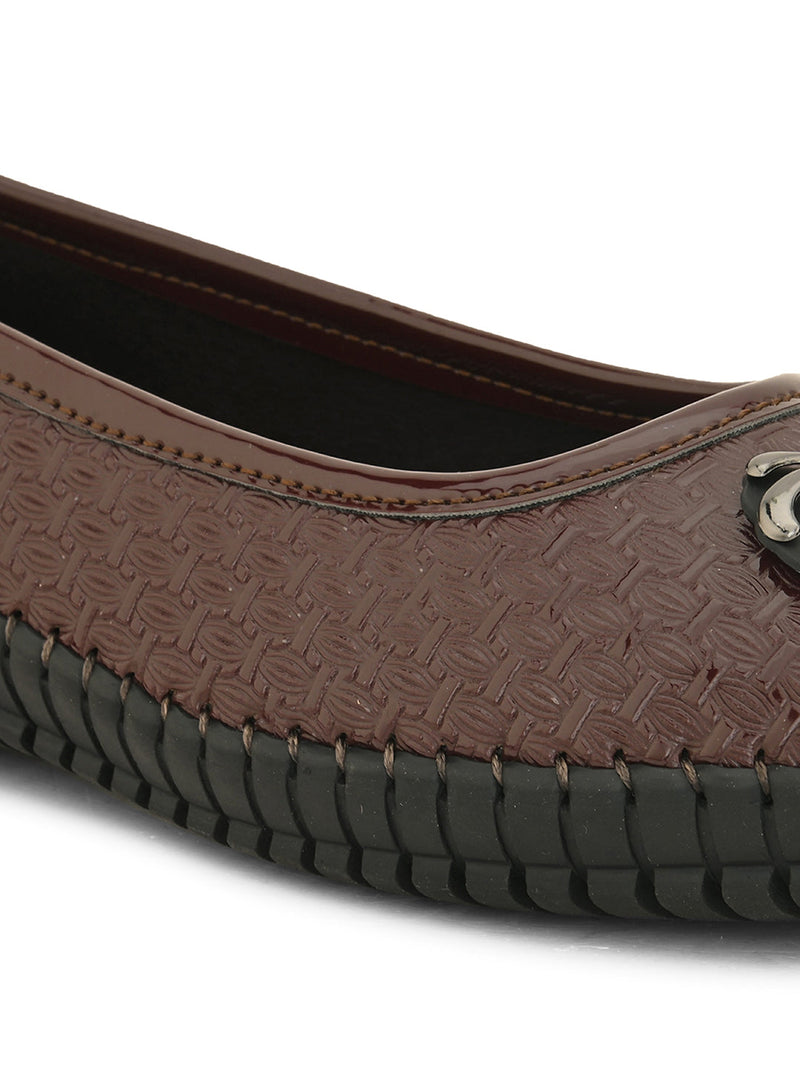 A brown woven-texture flat shoe with a round metal ornament on the toe and a black rubber sole.
