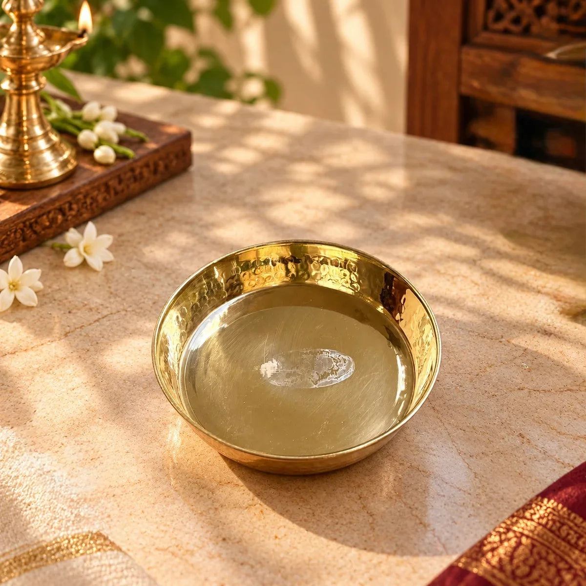 Brass Pooja Plate Small on a marble pooja altar with a lit brass diya and jasmine flowers, handcrafted for daily pooja. Zishta Return Gifts.