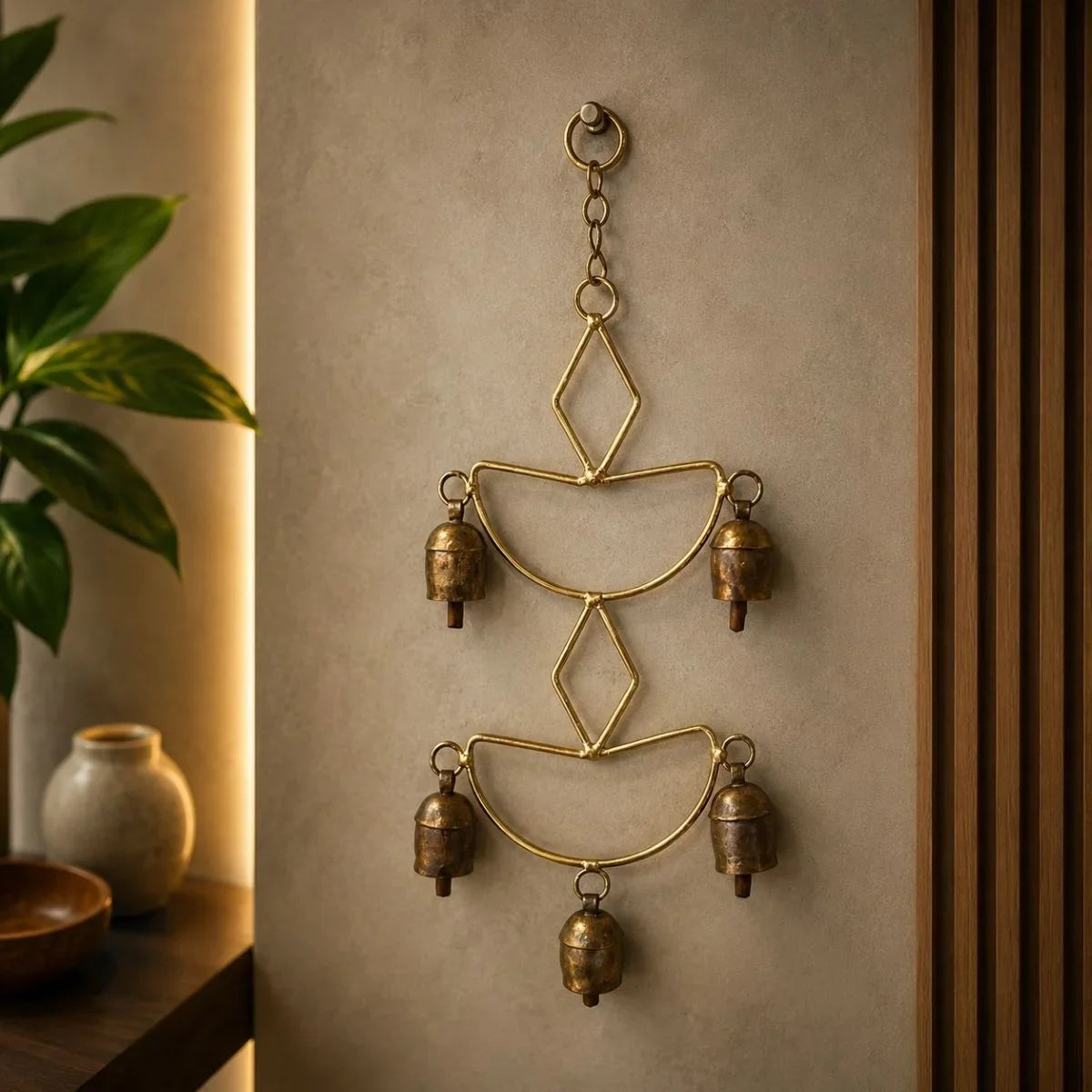 Copper coated iron wall hanging with five decorative bells in a living room. Zishta Home Decor.