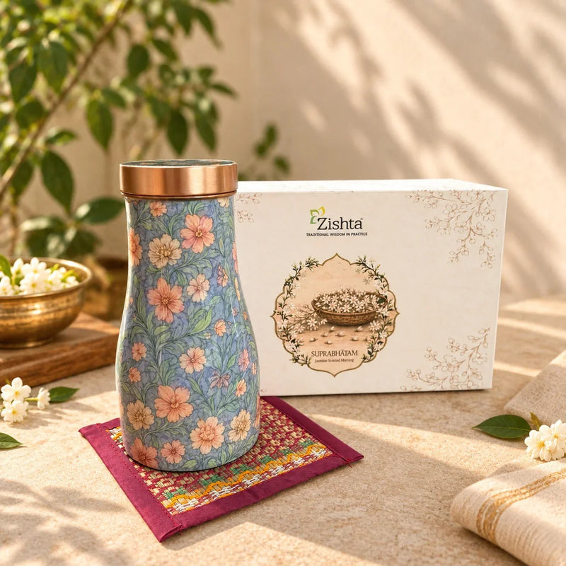 Closed copper enamel flower carafe on a handwoven Madur coaster next to the Zishta Suprabhatam gift box. Zishta Diwali Corporate Gifting.