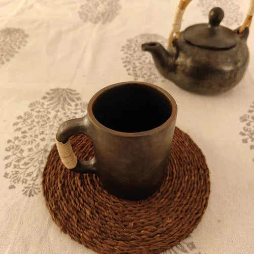 Manipur Black  Pottery Milk Cup and teapot on a textured surface with a woven coaster-Zishta Traditional Serveware